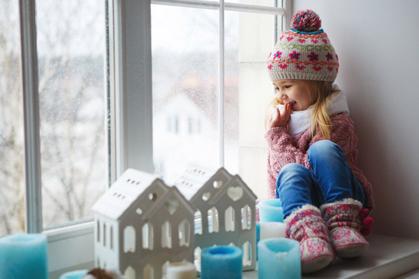 little girl sitting by window in a home heated with fuel oil