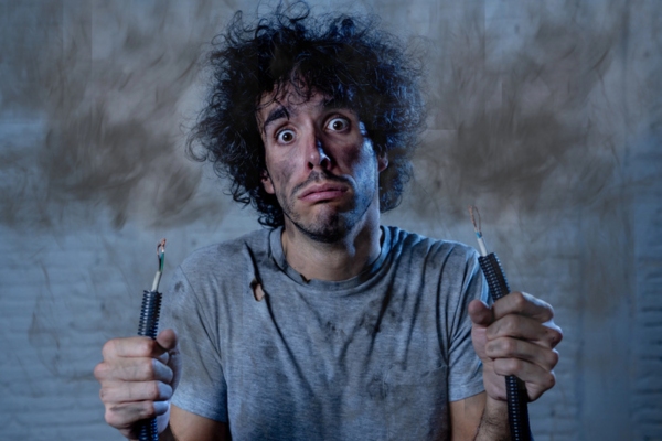 image of a man with burns and smoke holding electrical cable depicting electrical dangers