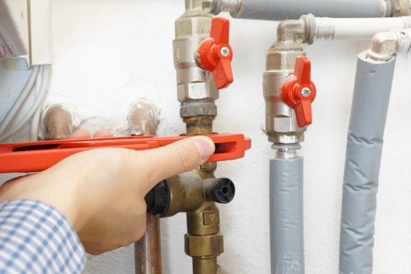 image of a man's hand adjusting pipes depicting boiler leaks