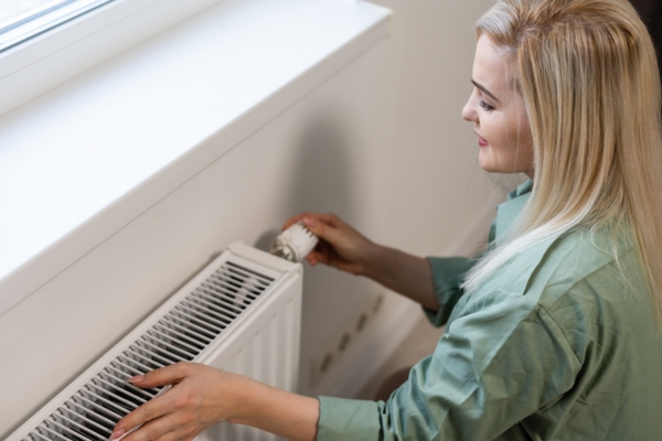 woman checking and adjusting heating radiator depicting issues