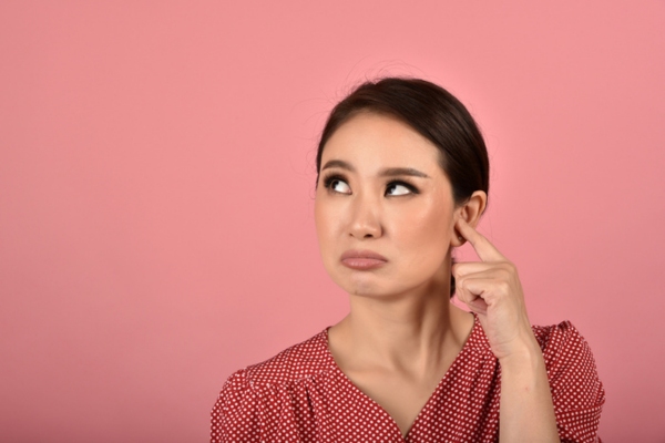 woman covering one ear with a finger wondering about unusual boiler noise