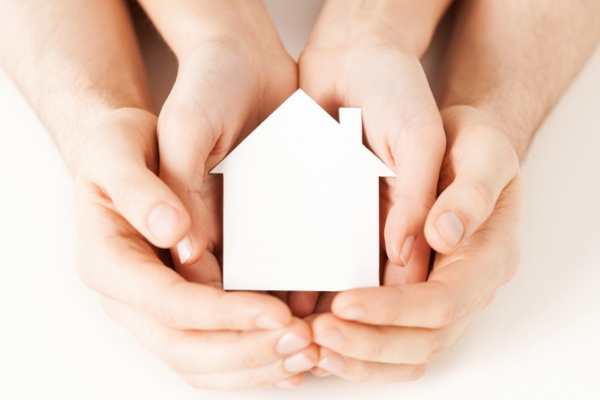 Man and woman hands with white paper house depicting protecting home from winter electrical issues