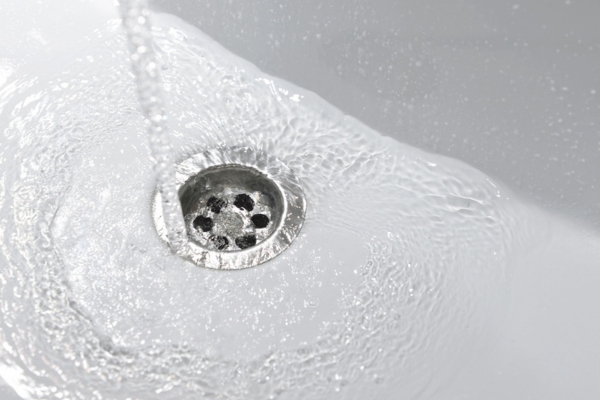 image of a water draining on white sink