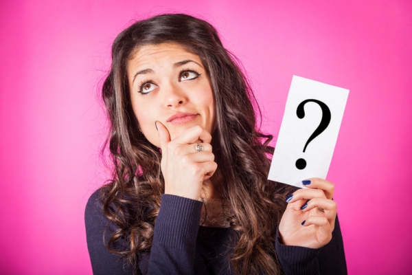 woman with a wondering face holding a question mark sign depicting FAQs about furnace & boiler