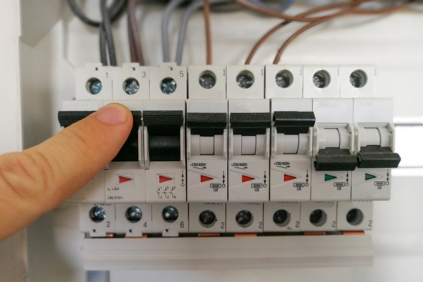 Male finger switching circuit breakers inside electrical panel