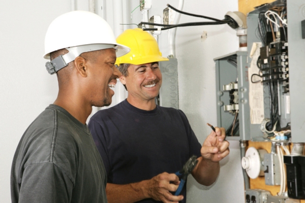 two electricians working on an electrical panel