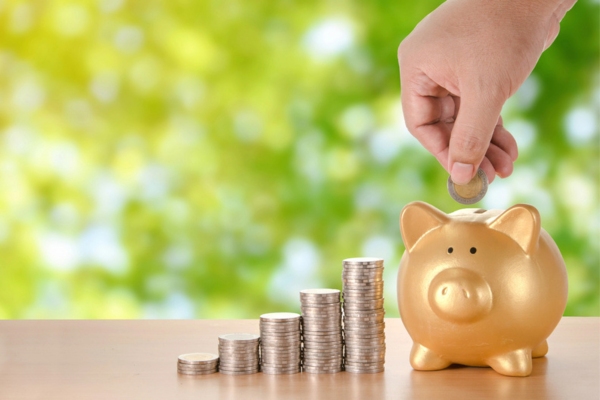 hand putting coins in a gold piggy bank depicting savings